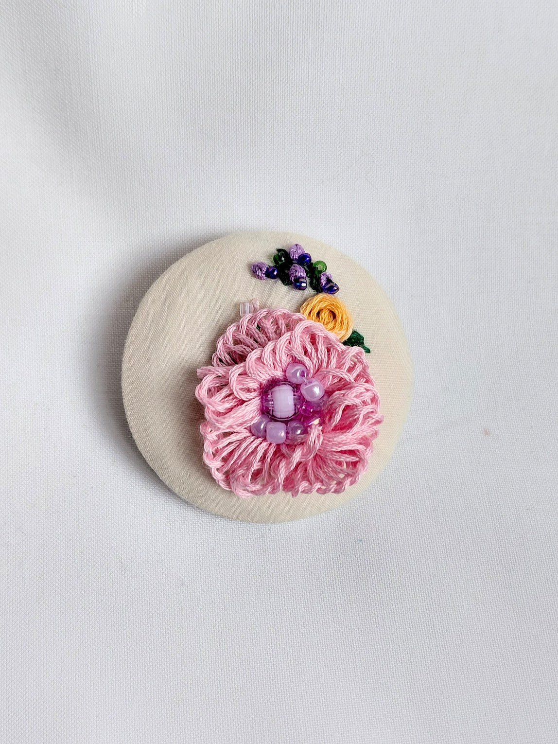 Decorative pink flower brooch on cream background