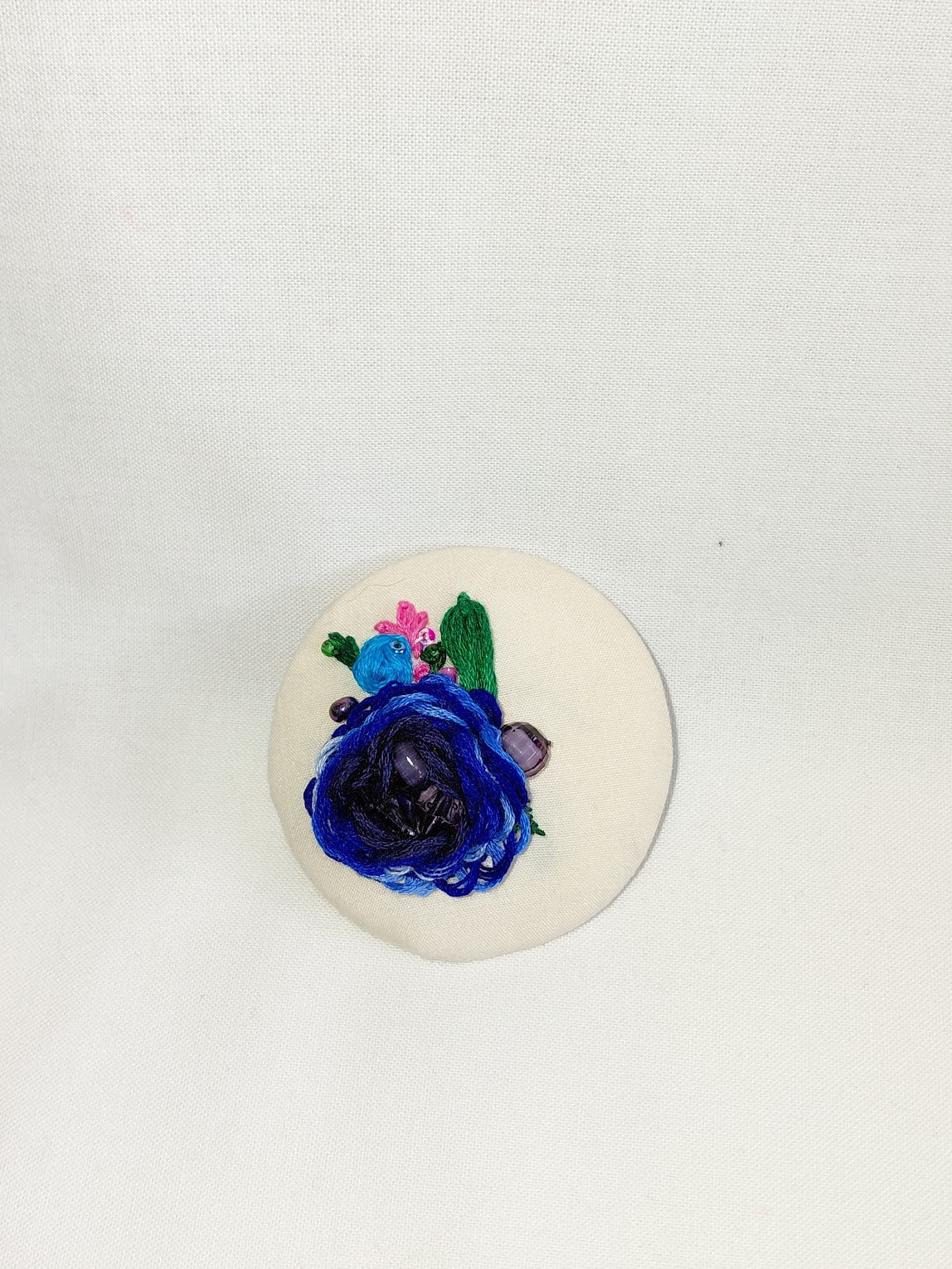 Decorative blue flower brooch on cream background