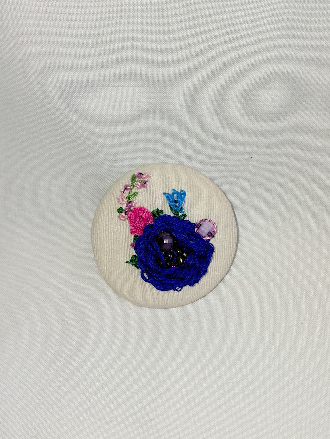 Decorative blue flower brooch on cream background
