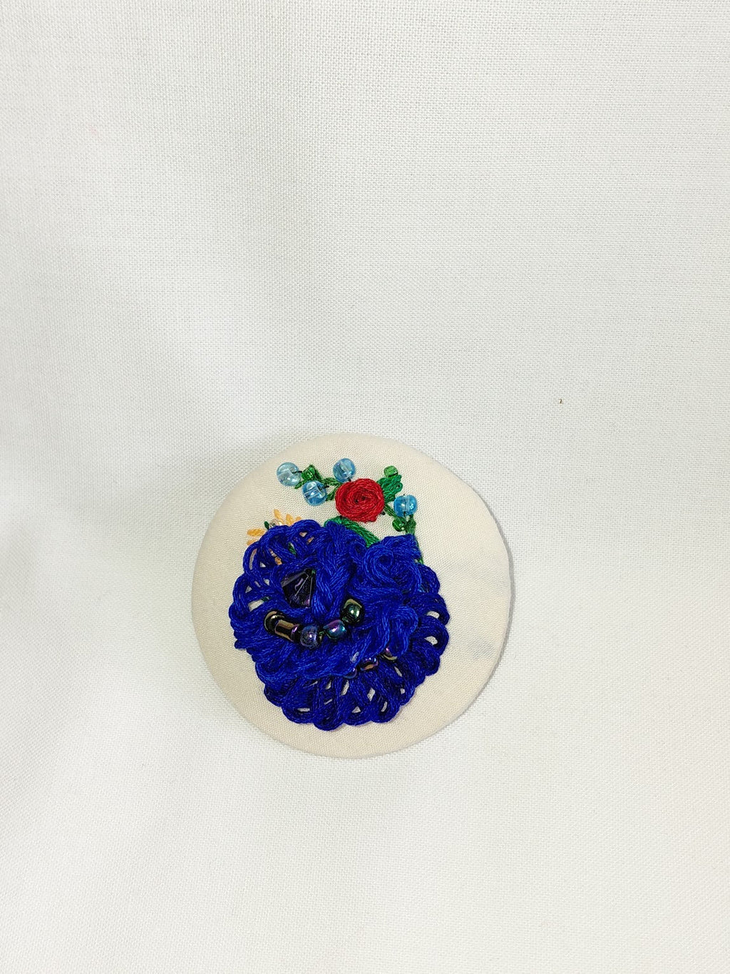 Decorative blue flower brooch on cream background