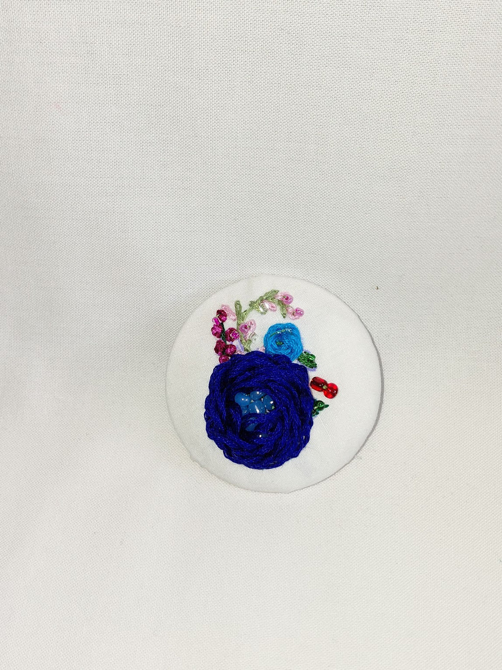 Decorative blue flower brooch on white background