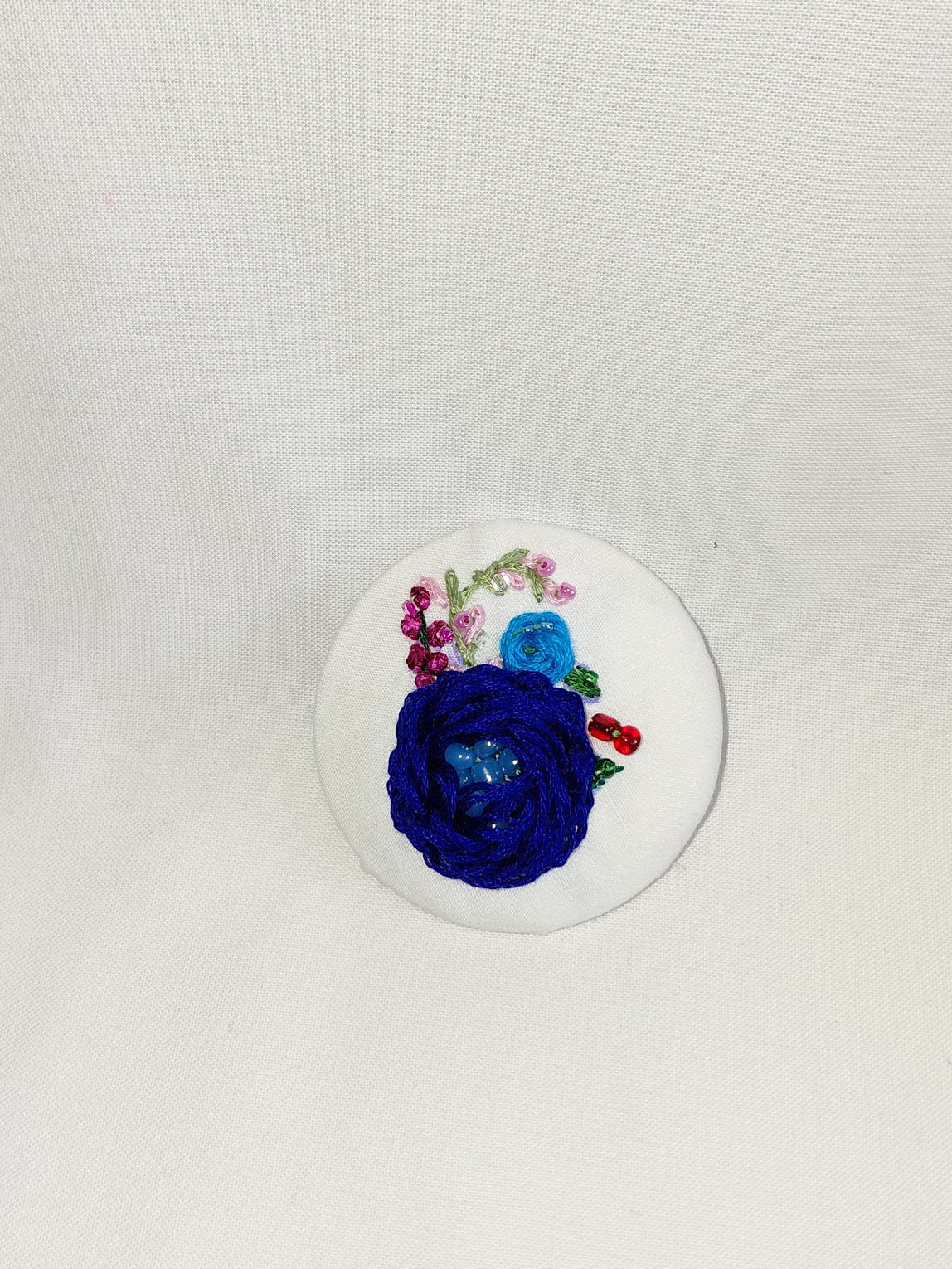 Decorative blue flower brooch on white background