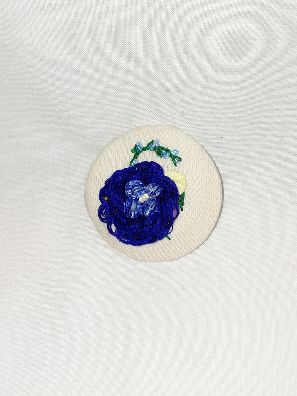 Decorative blue flower brooch on cream background