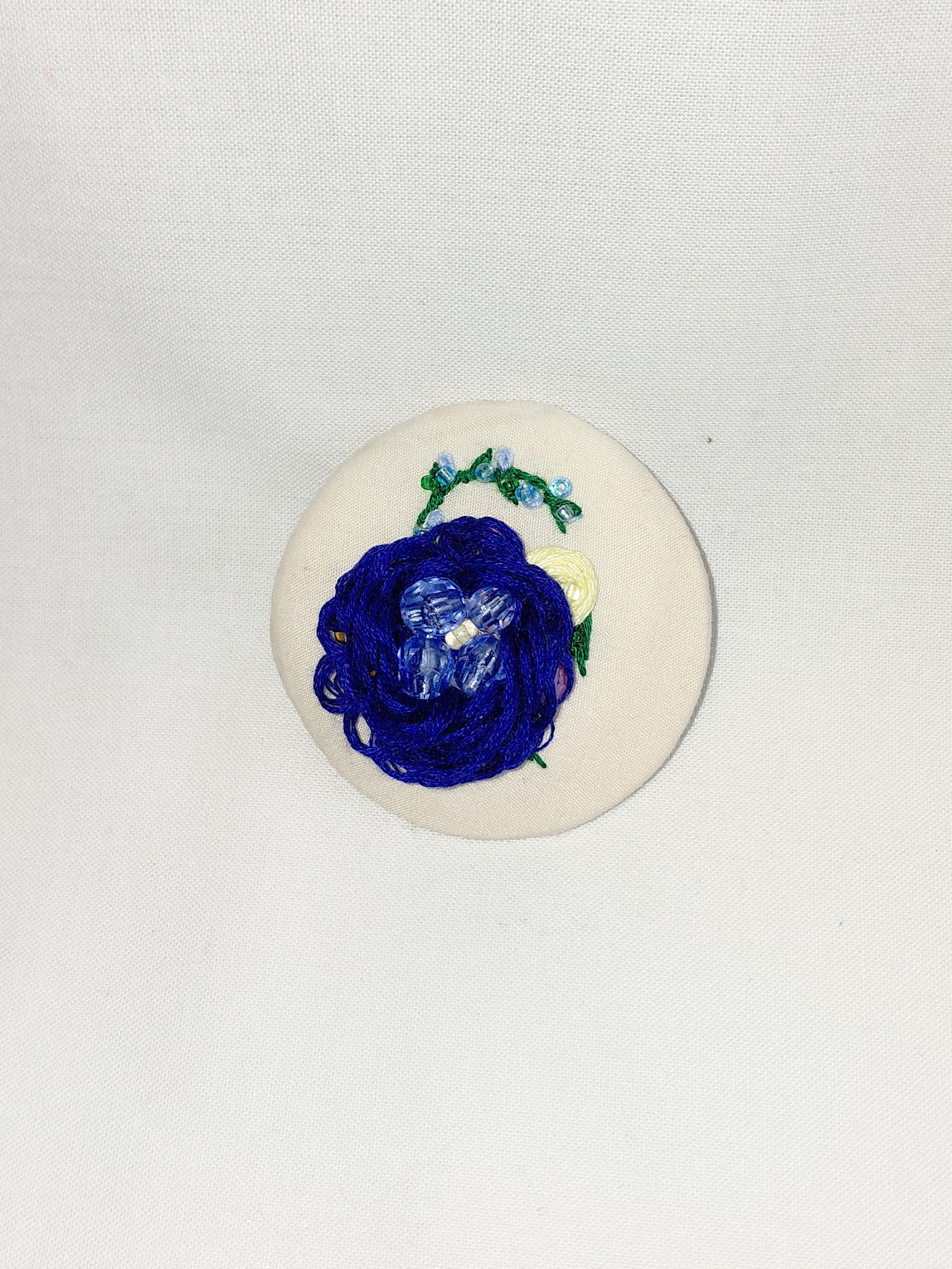 Decorative blue flower brooch on cream background