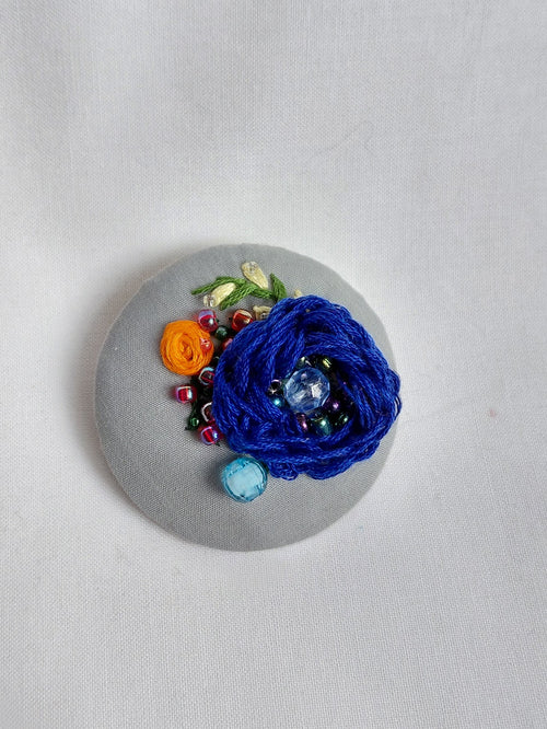 Decorative blue flower brooch on grey background