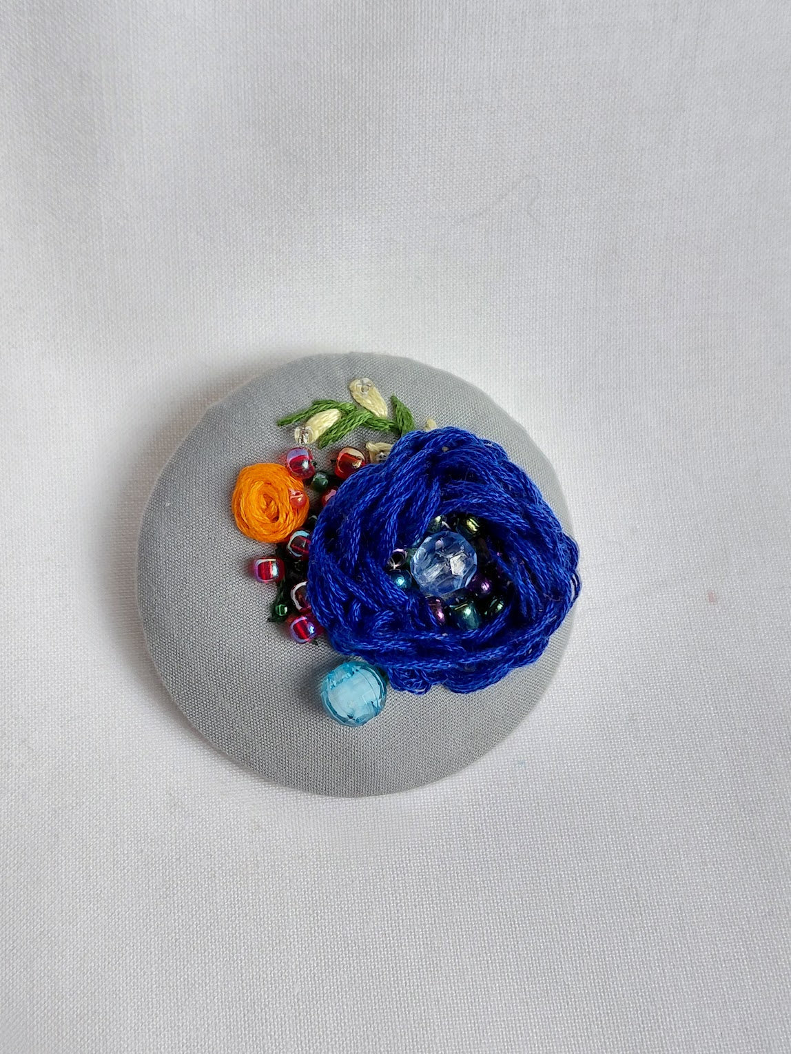 Decorative blue flower brooch on grey background
