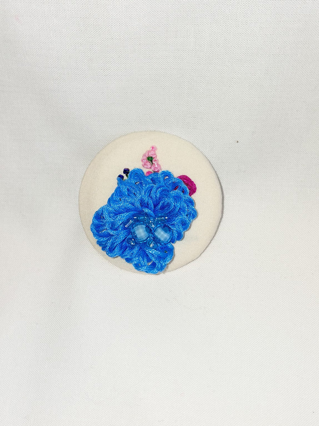 Decorative blue flower brooch on cream background