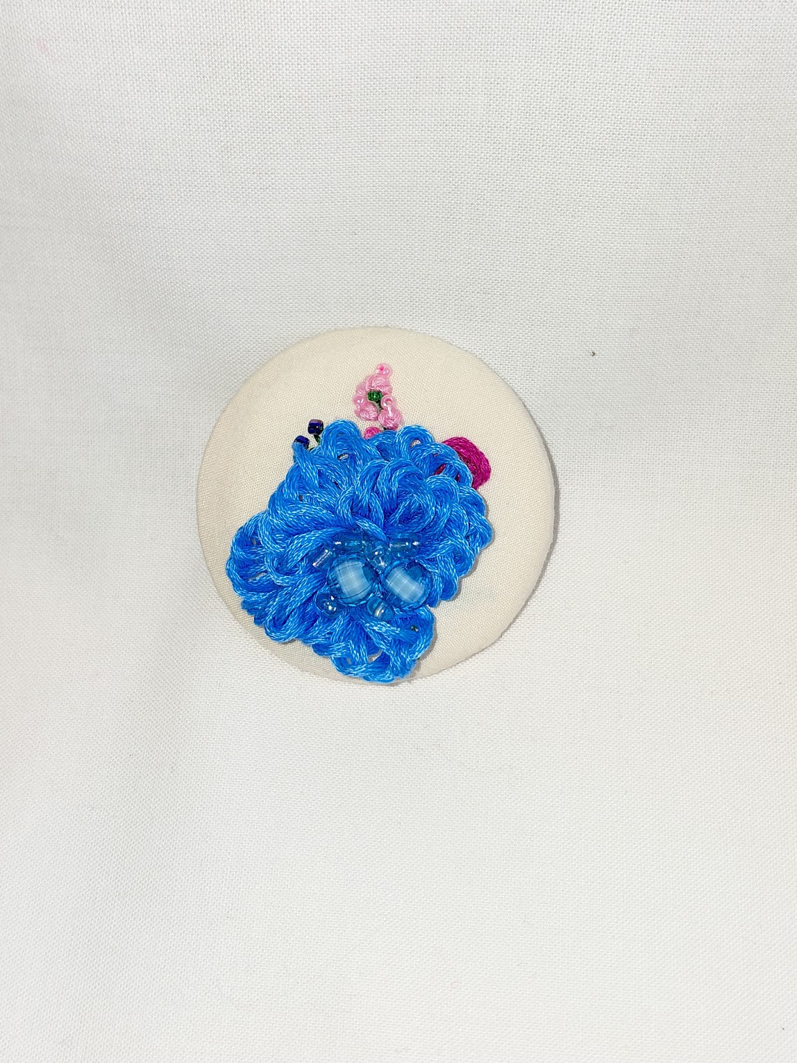 Decorative blue flower brooch on cream background