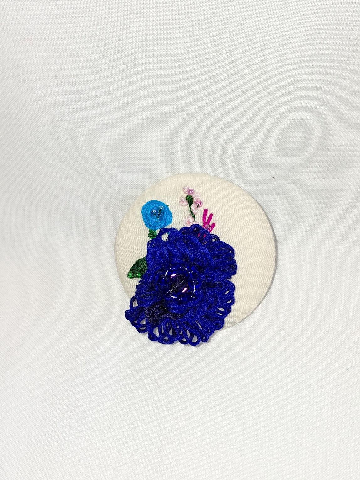 Decorative blue flower brooch on cream background