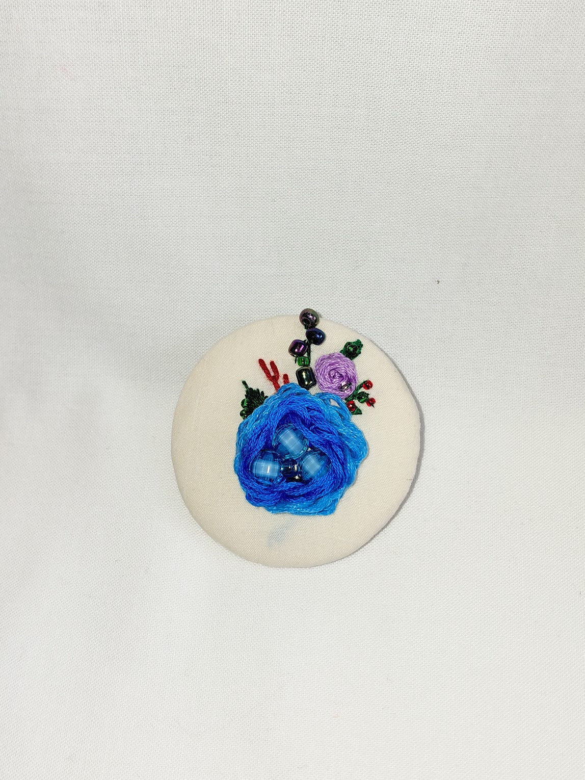 Decorative blue flower brooch on cream background