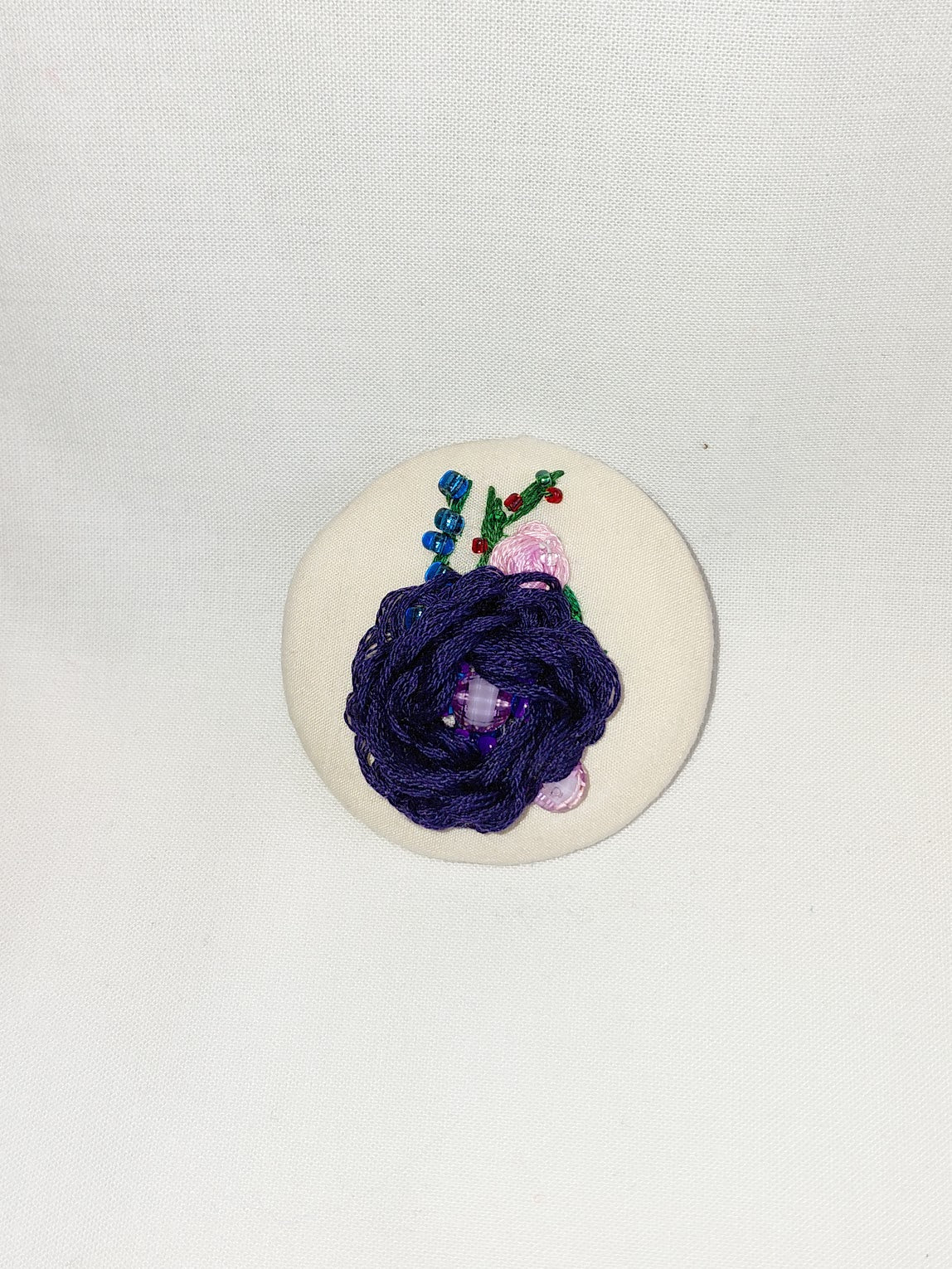 Decorative blue flower brooch on cream background