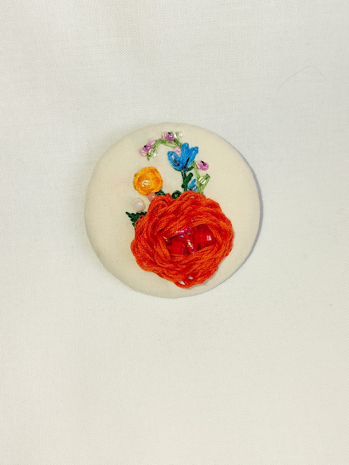 Decorative orange flower brooch on cream background