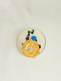 Decorative orange flower brooch on cream background