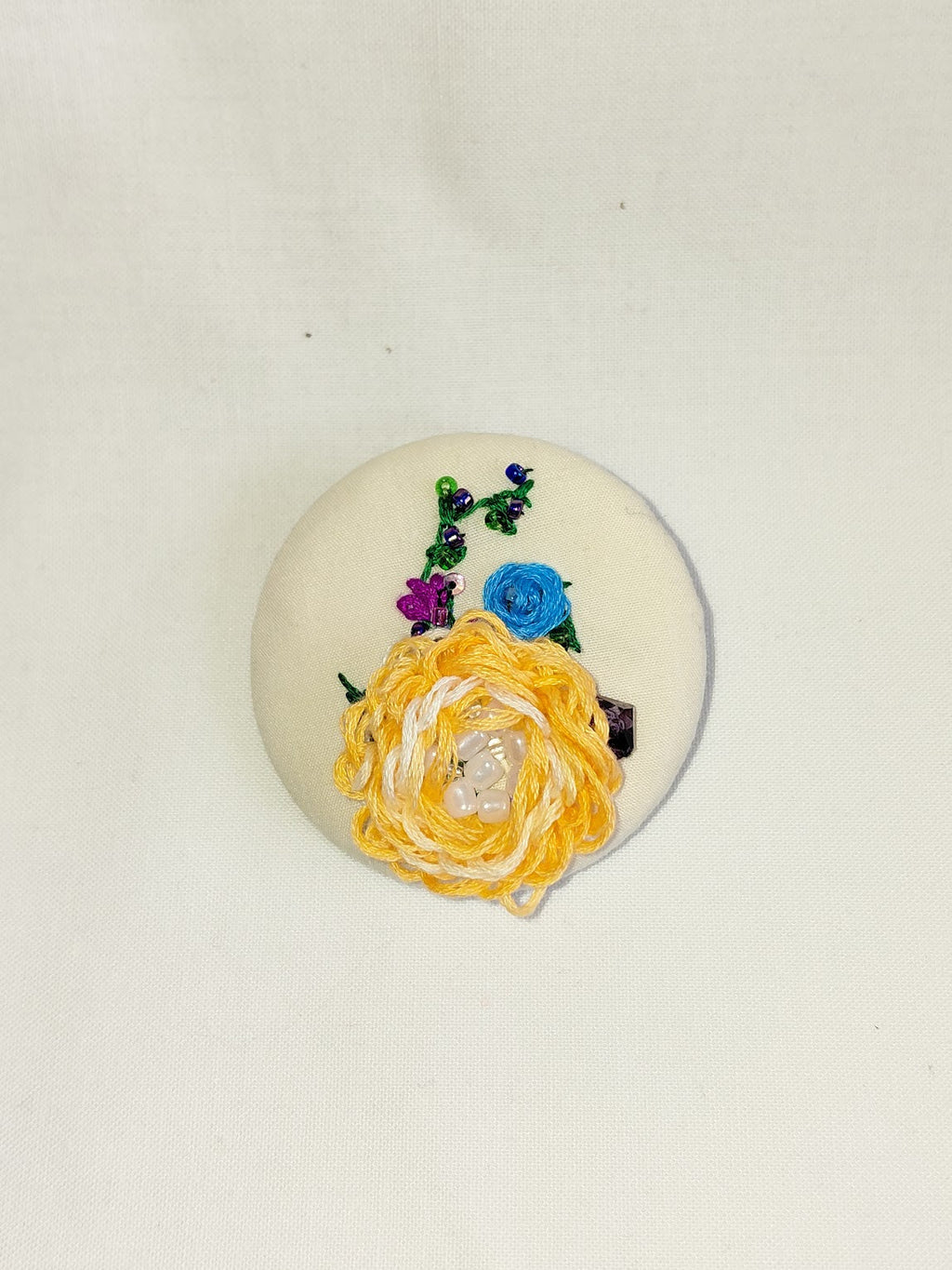 Decorative orange flower brooch on cream background