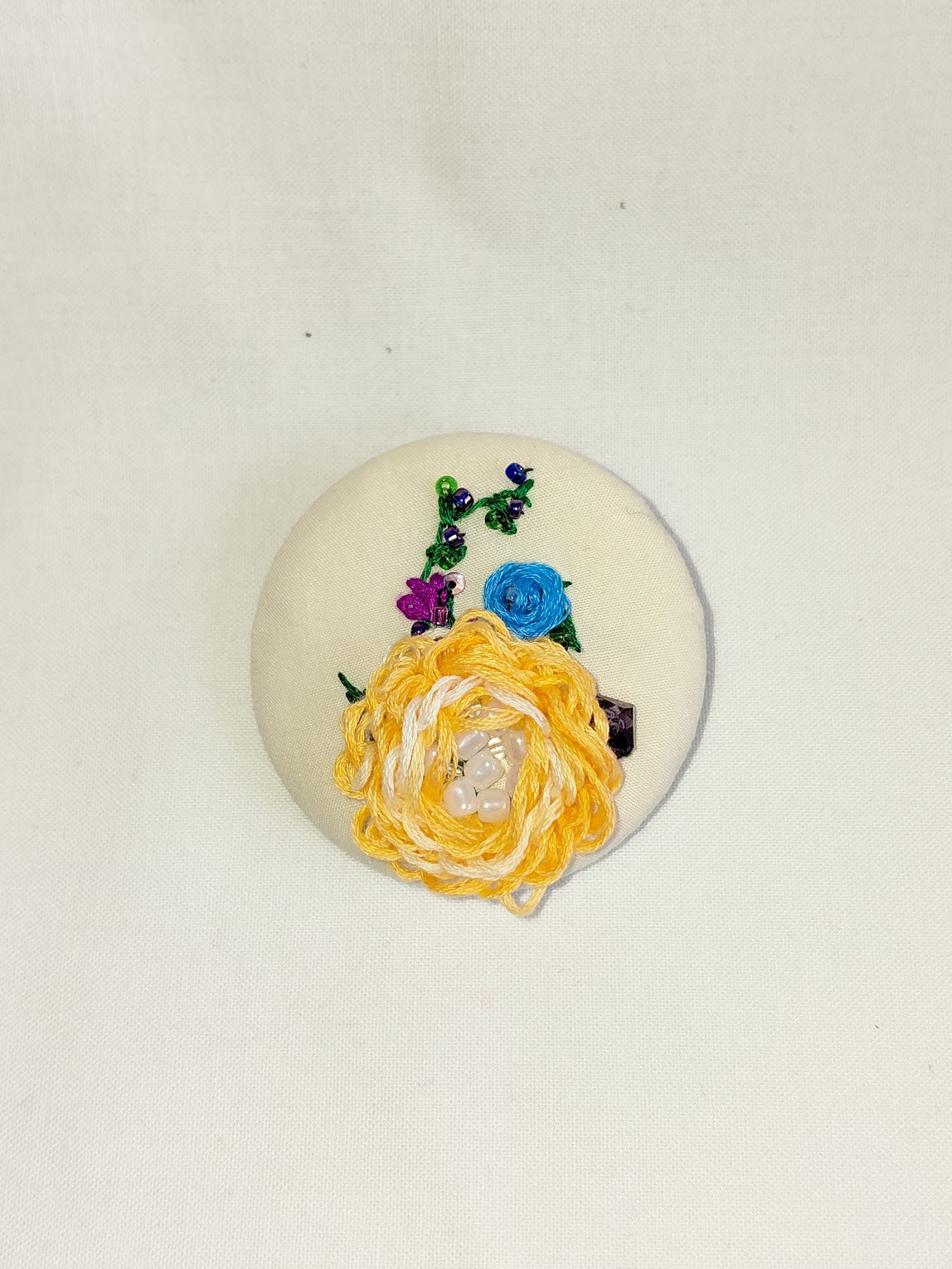 Decorative orange flower brooch on cream background