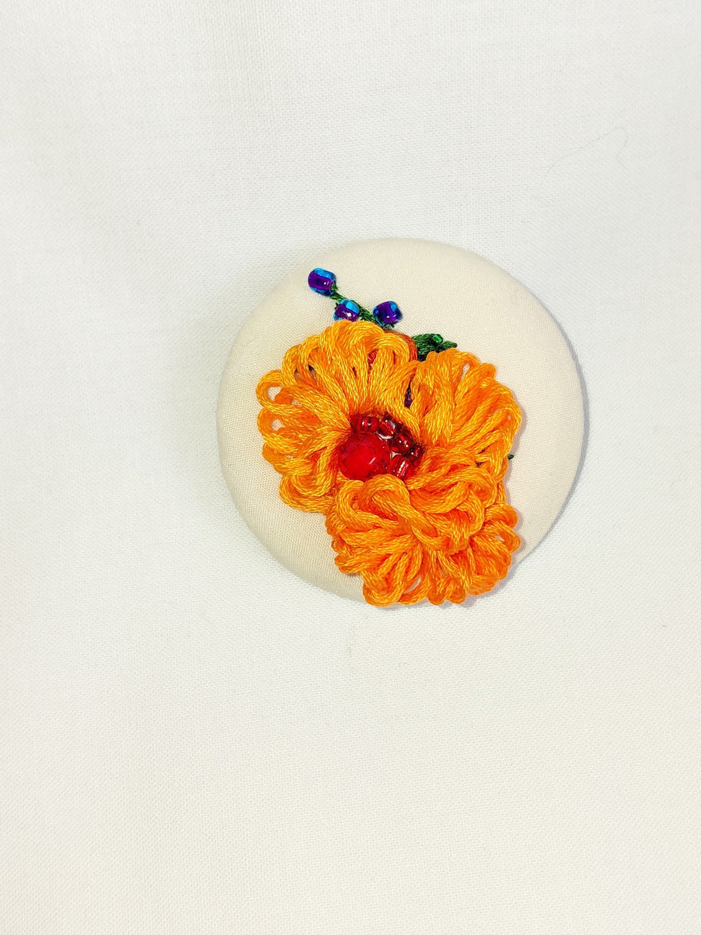 Decorative orange flower brooch on cream background