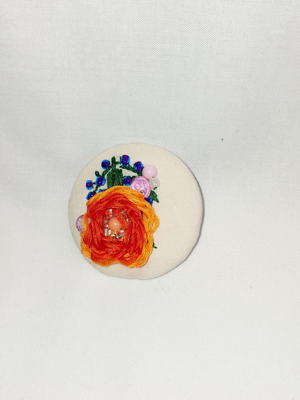 Decorative orange flower brooch on cream background