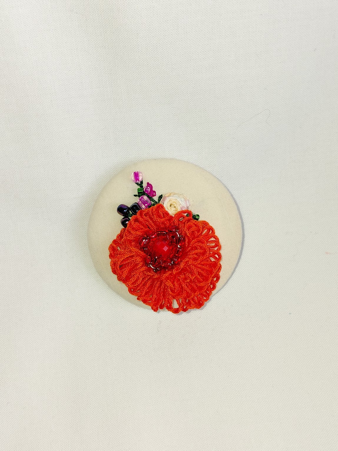 Decorative orange flower brooch on cream background