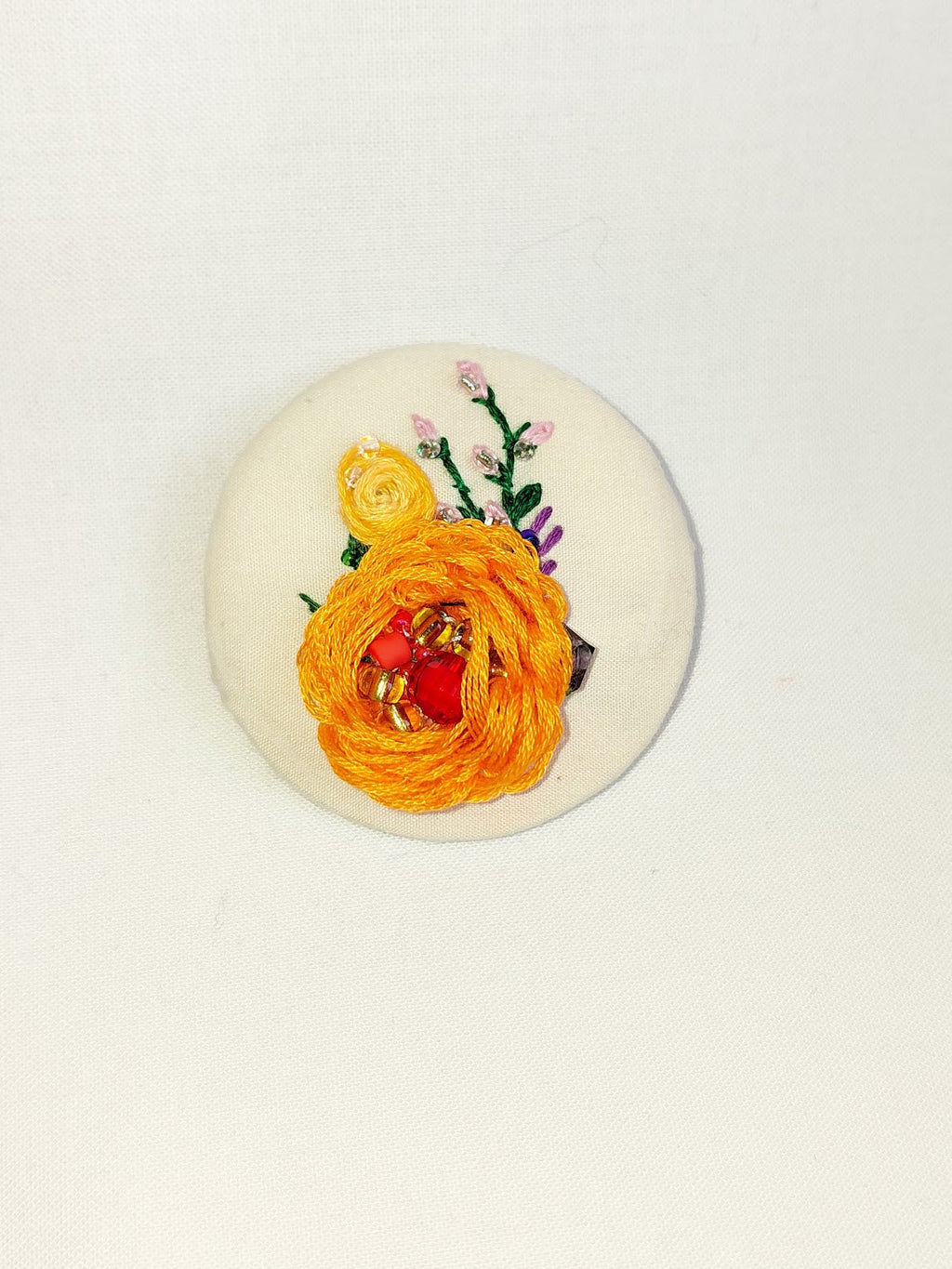 Decorative orange flower brooch on cream background