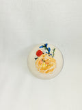 Decorative orange flower brooch on cream background