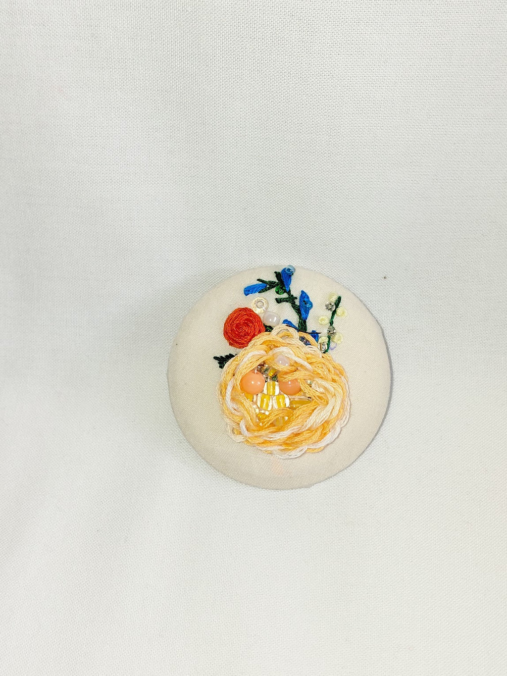 Decorative orange flower brooch on cream background