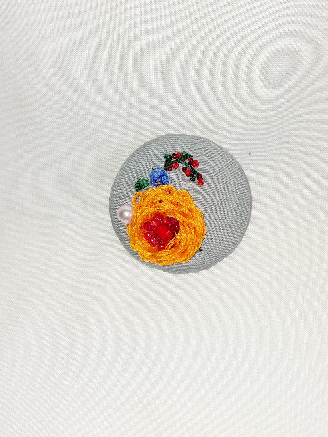 Decorative orange flower brooch on grey background