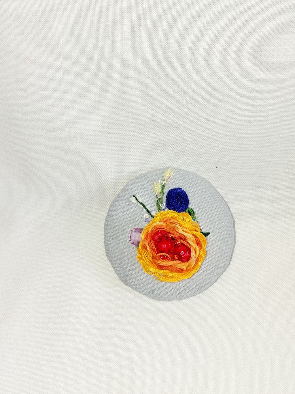 Decorative orange flower brooch on blue spec background
