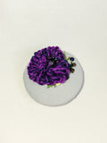 Decorative purple flower brooch on blue spec background
