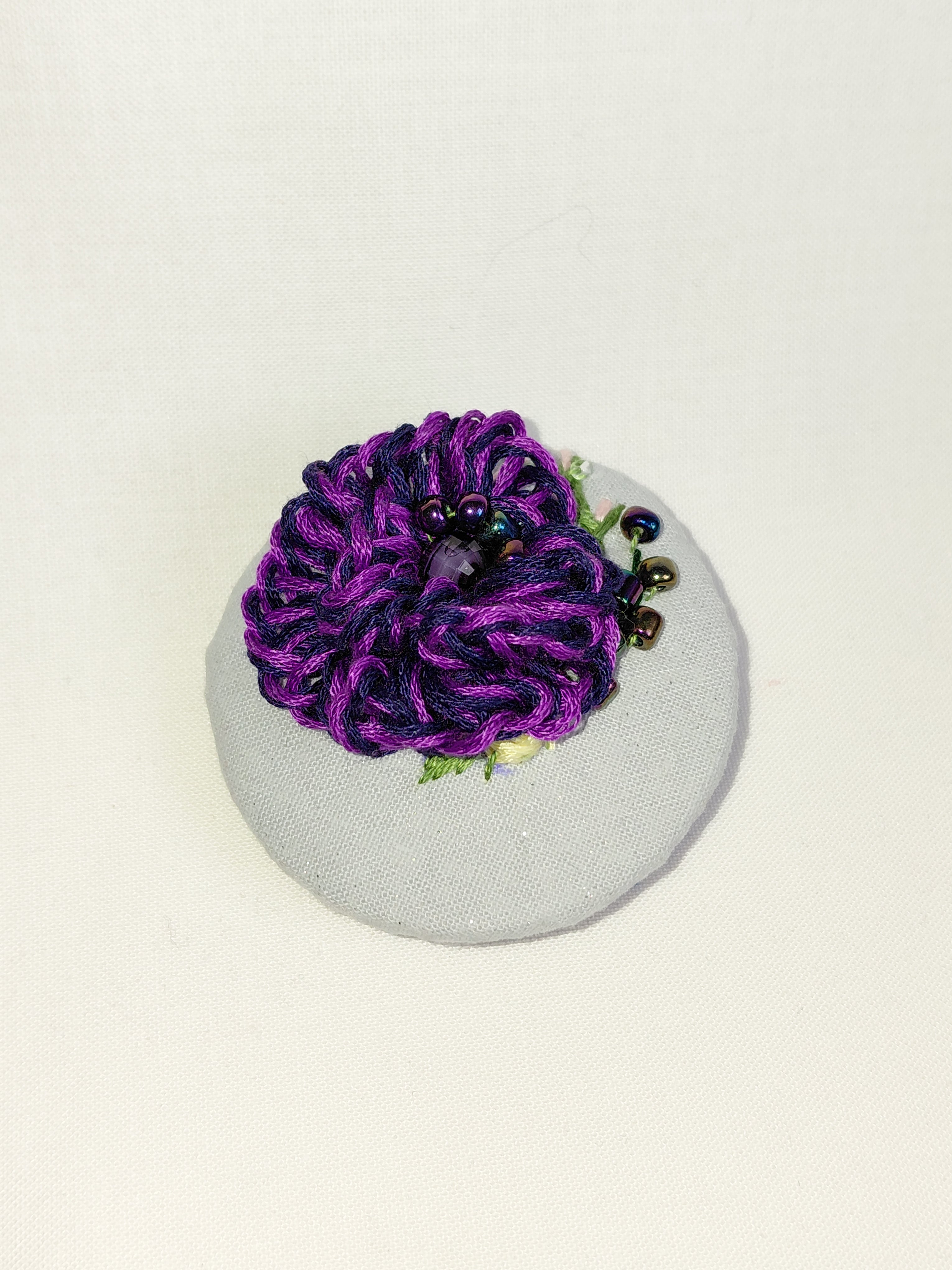 Decorative purple flower brooch on blue spec background