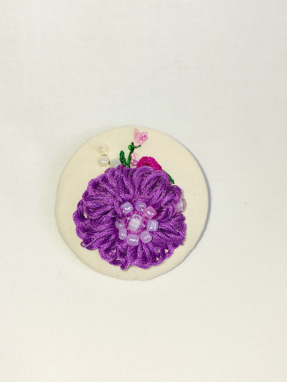 Decorative purple flower brooch on cream background