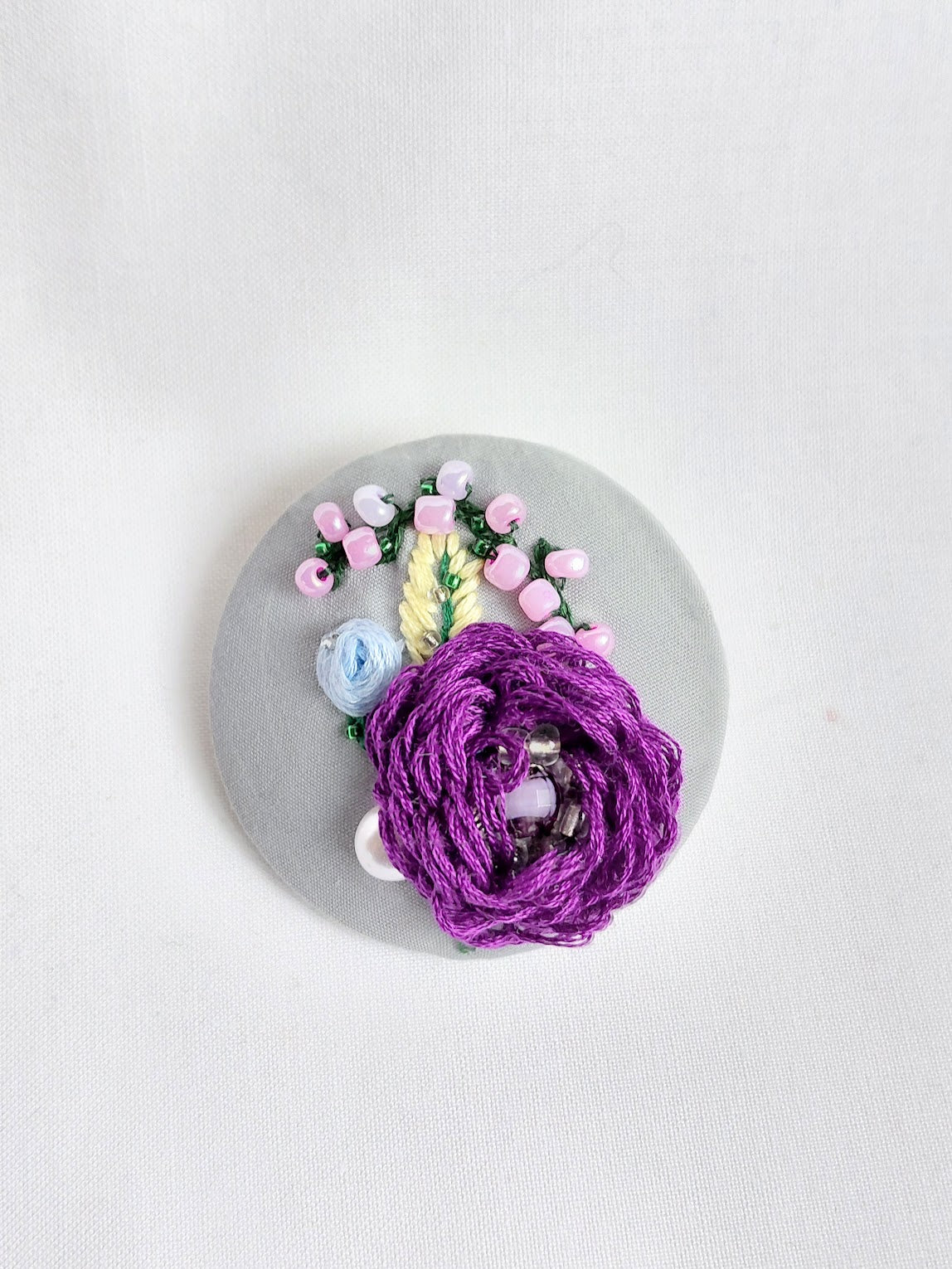 Decorative purple flower brooch on grey background