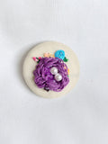 Decorative purple flower brooch on cream background