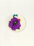 Decorative purple flower brooch on cream background