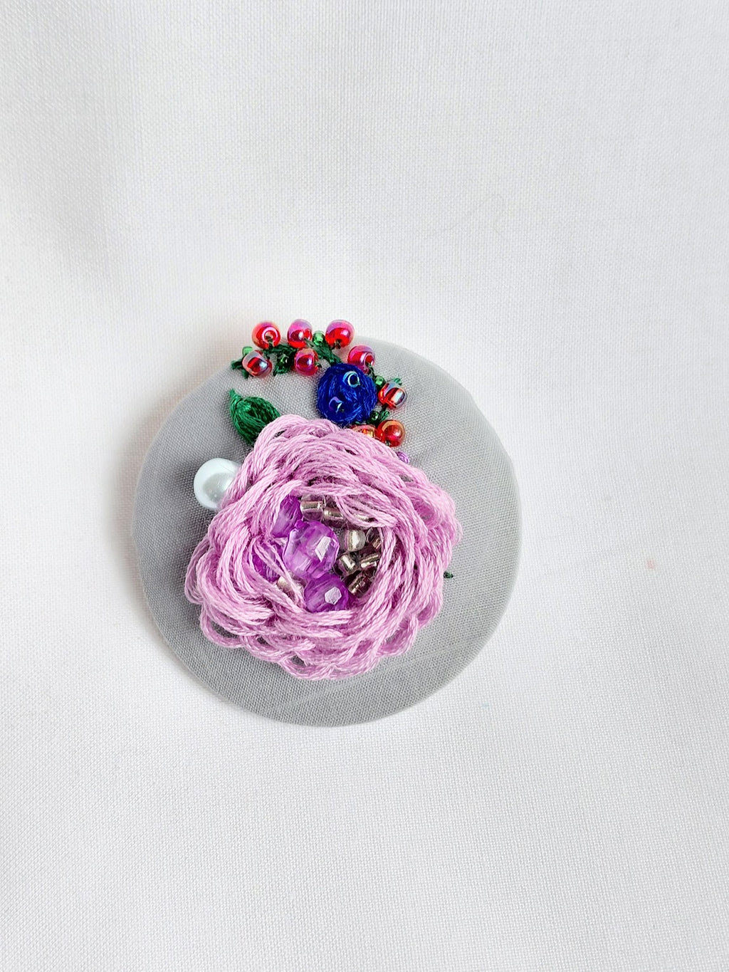 Decorative purple flower brooch on grey background
