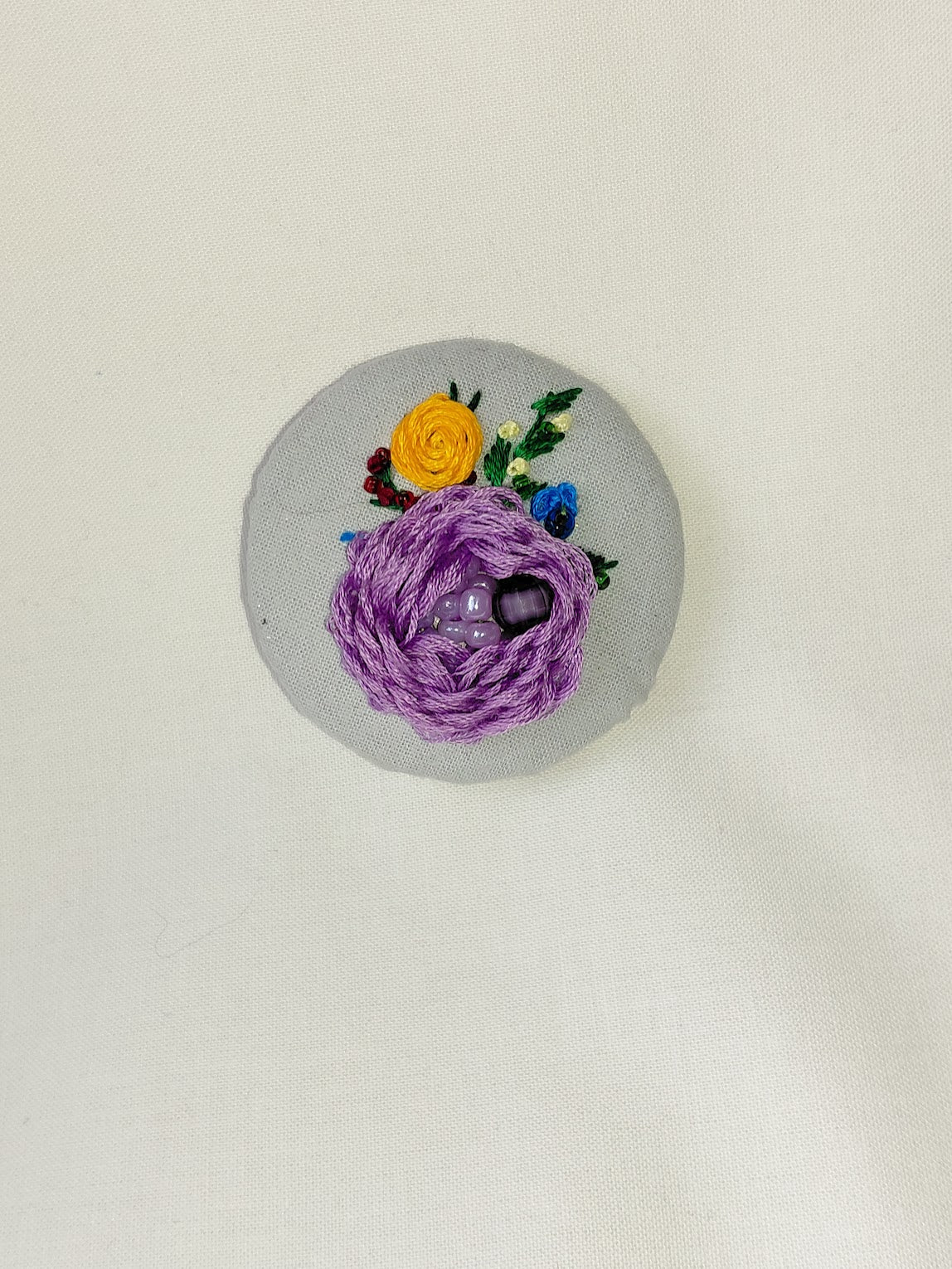Decorative purple flower brooch on blue spec background