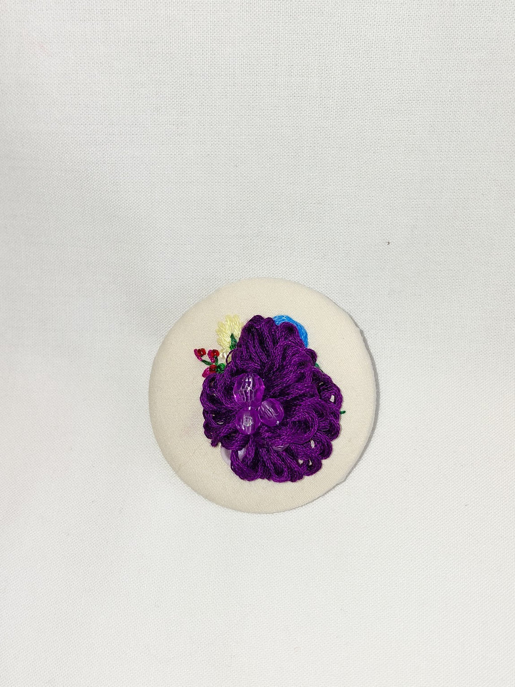 Decorative purple flower brooch on cream background