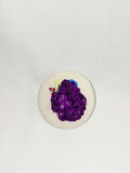 Decorative purple flower brooch on cream background