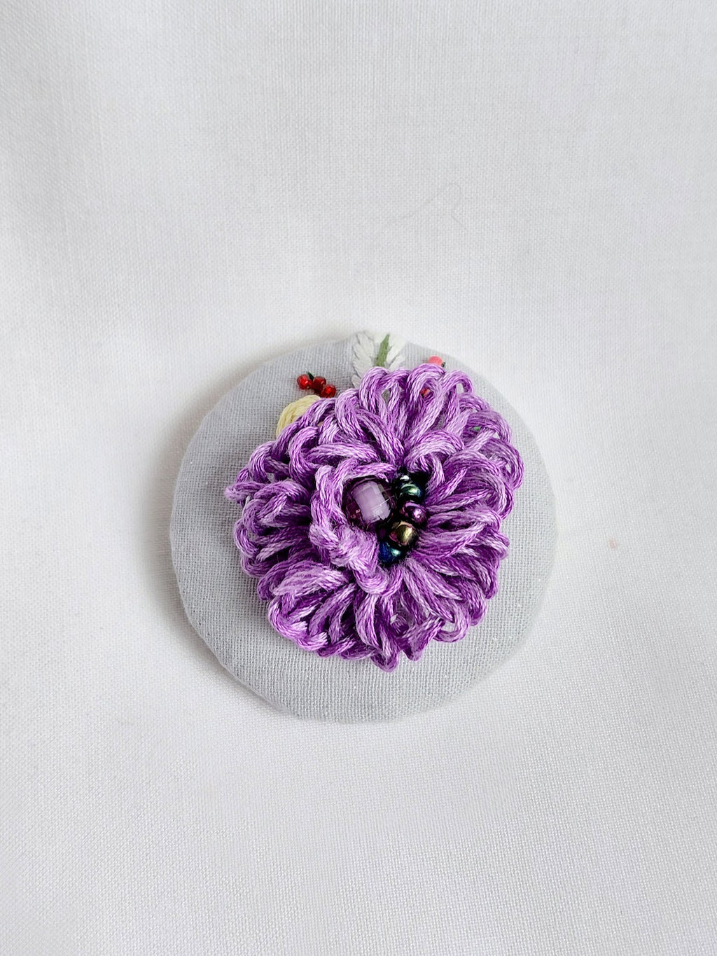 Decorative purple flower brooch on blue spec background