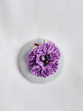Decorative purple flower brooch on blue spec background