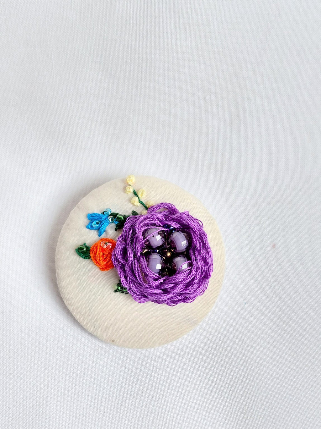 Decorative purple flower brooch on cream background