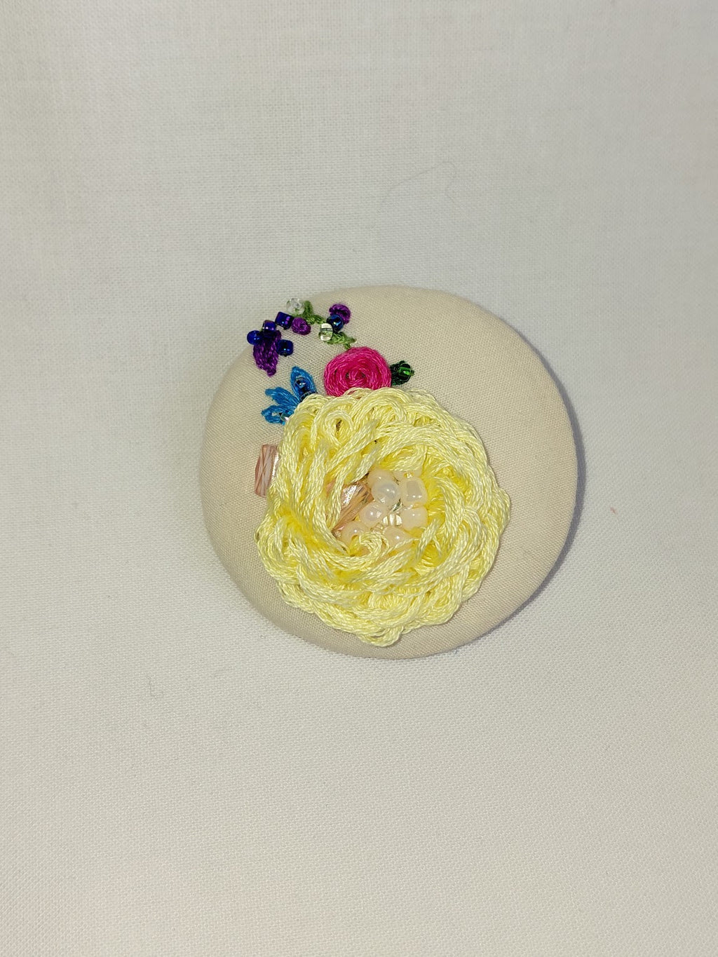 Decorative yellow flower brooch on cream background