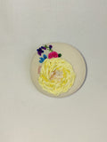 Decorative yellow flower brooch on cream background