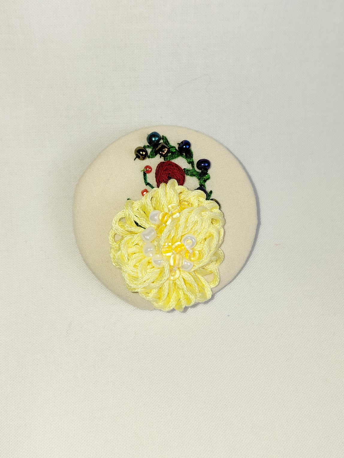 Decorative yellow flower brooch on cream background