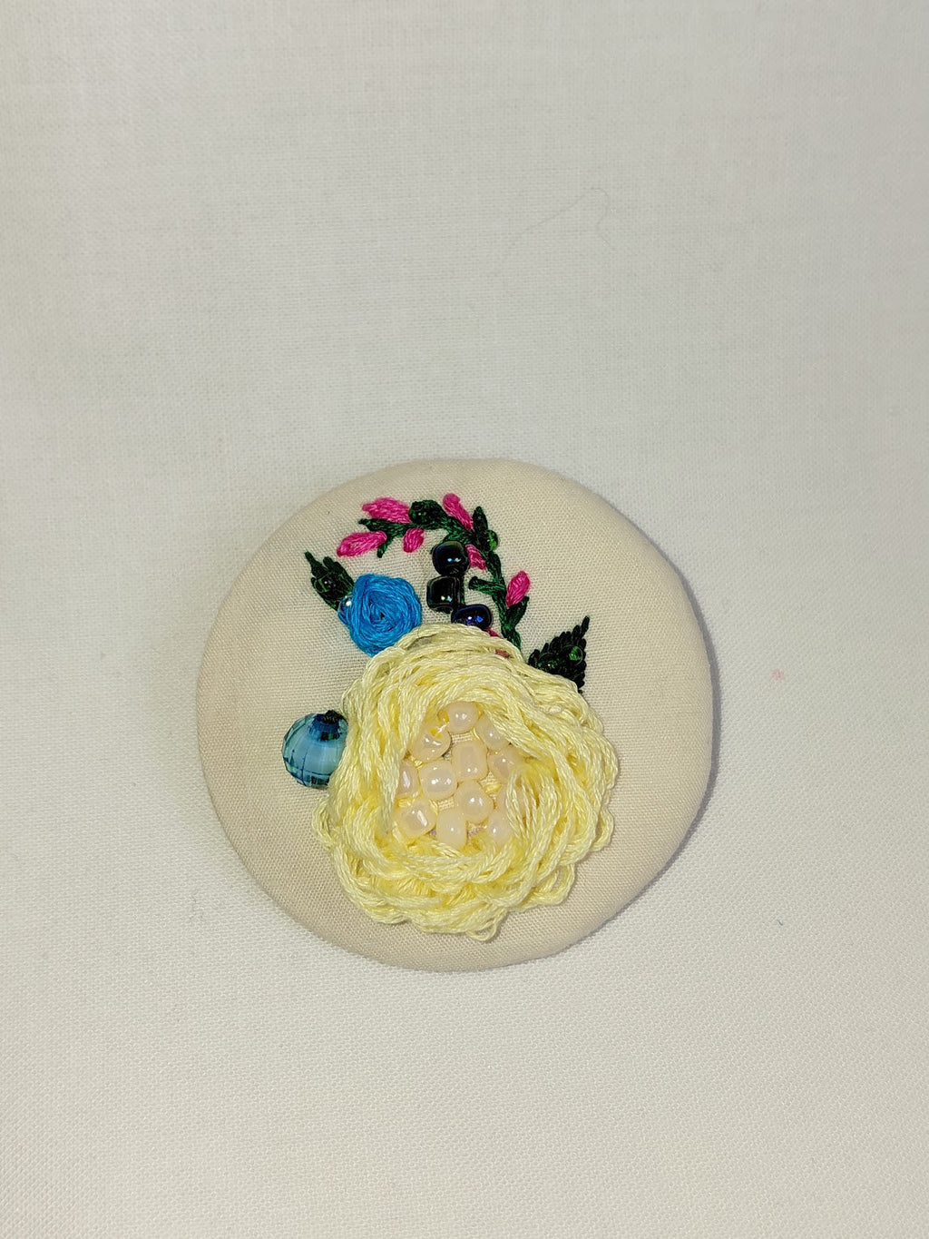 Decorative yellow flower brooch on cream background