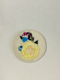 Decorative yellow flower brooch on cream background