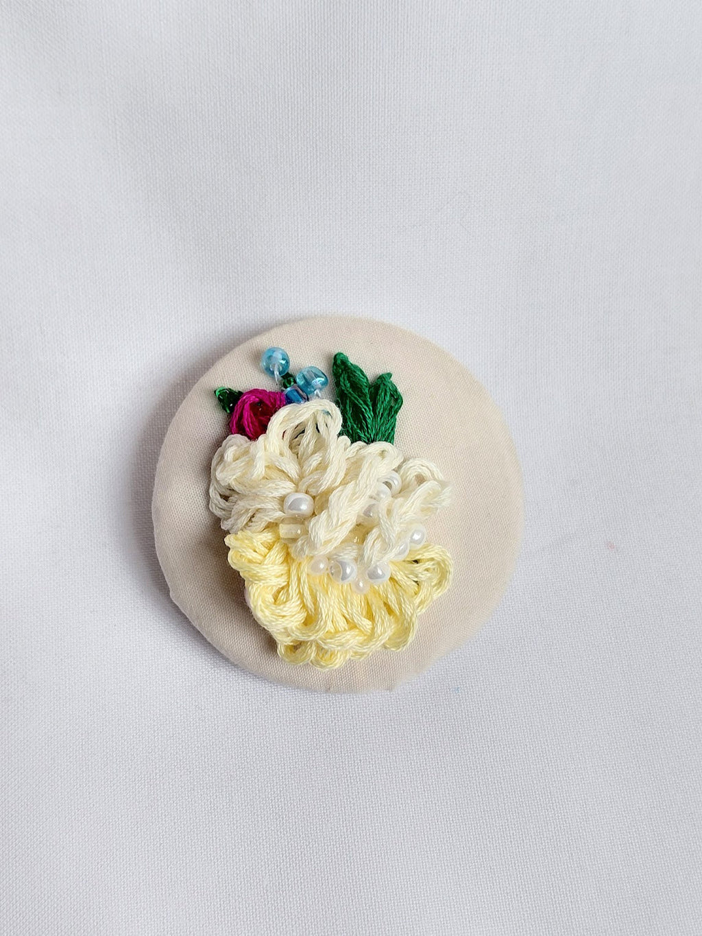 Decorative yellow flower brooch on cream background