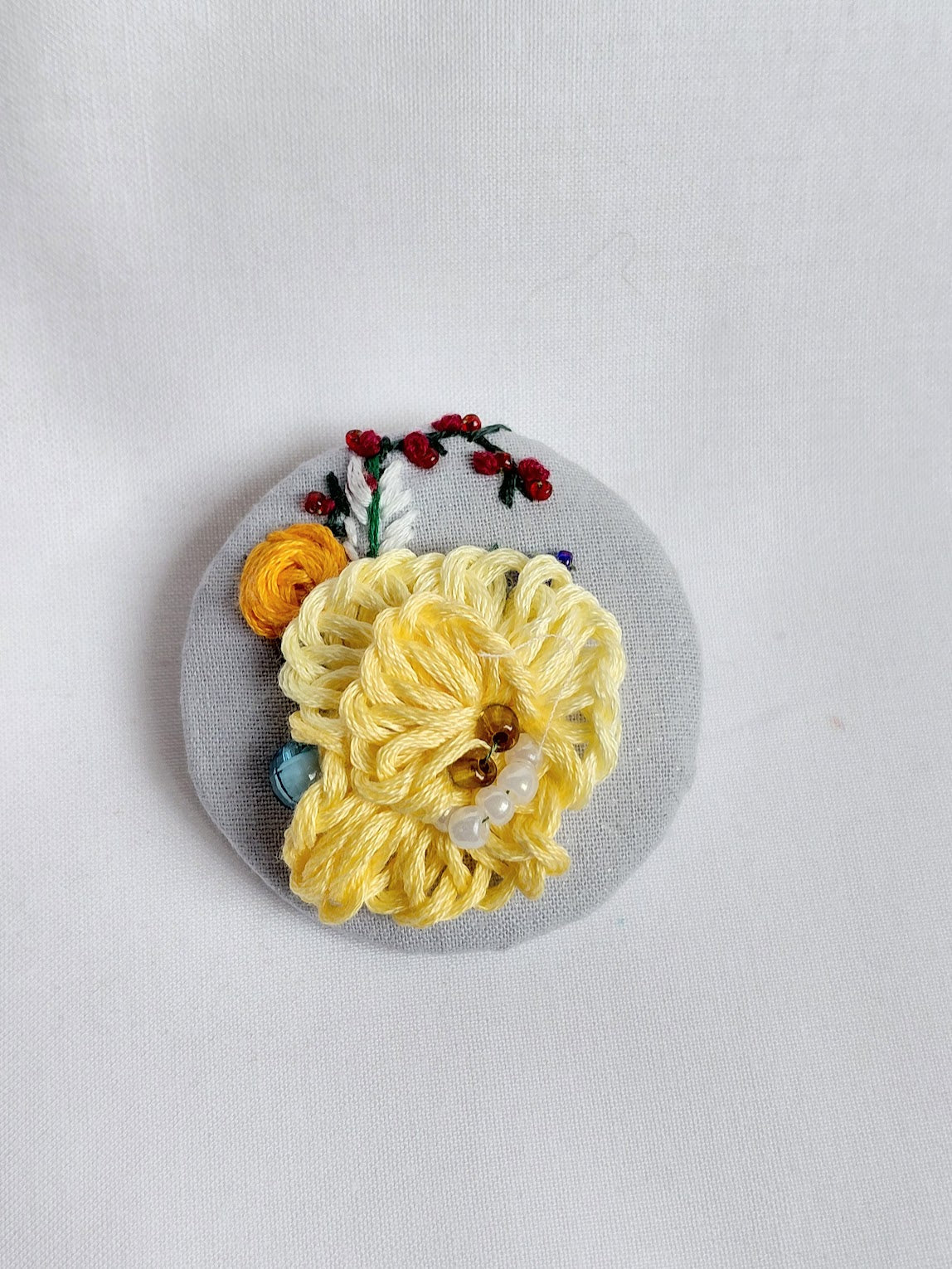 Decorative yellow flower brooch on blue spec background