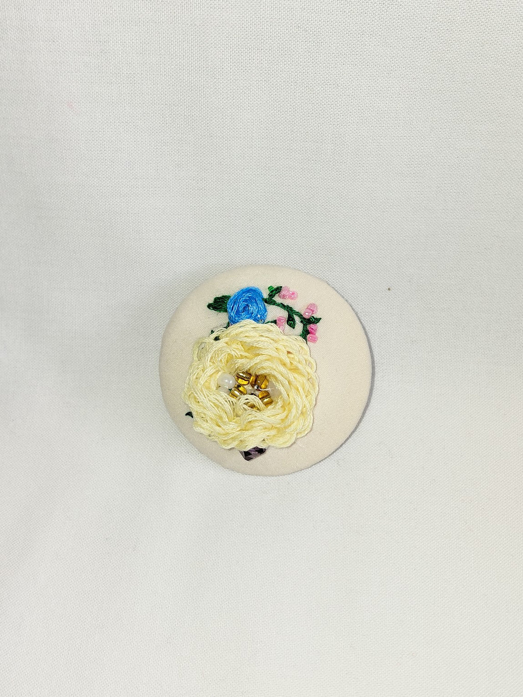 Decorative yellow flower brooch on cream background