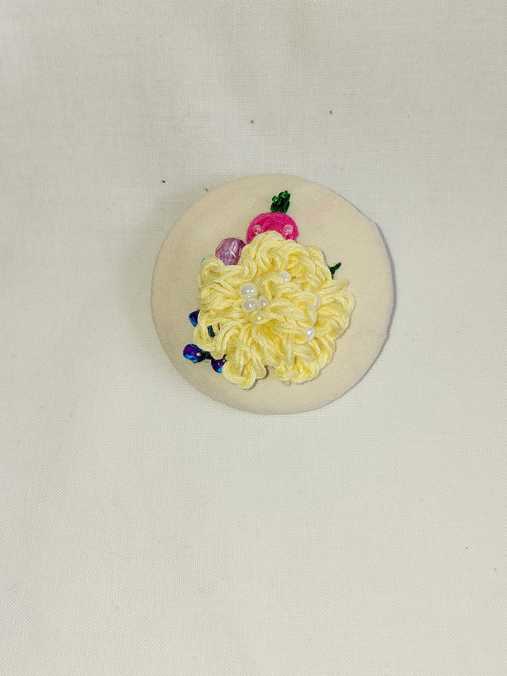 Decorative yellow flower brooch on cream background