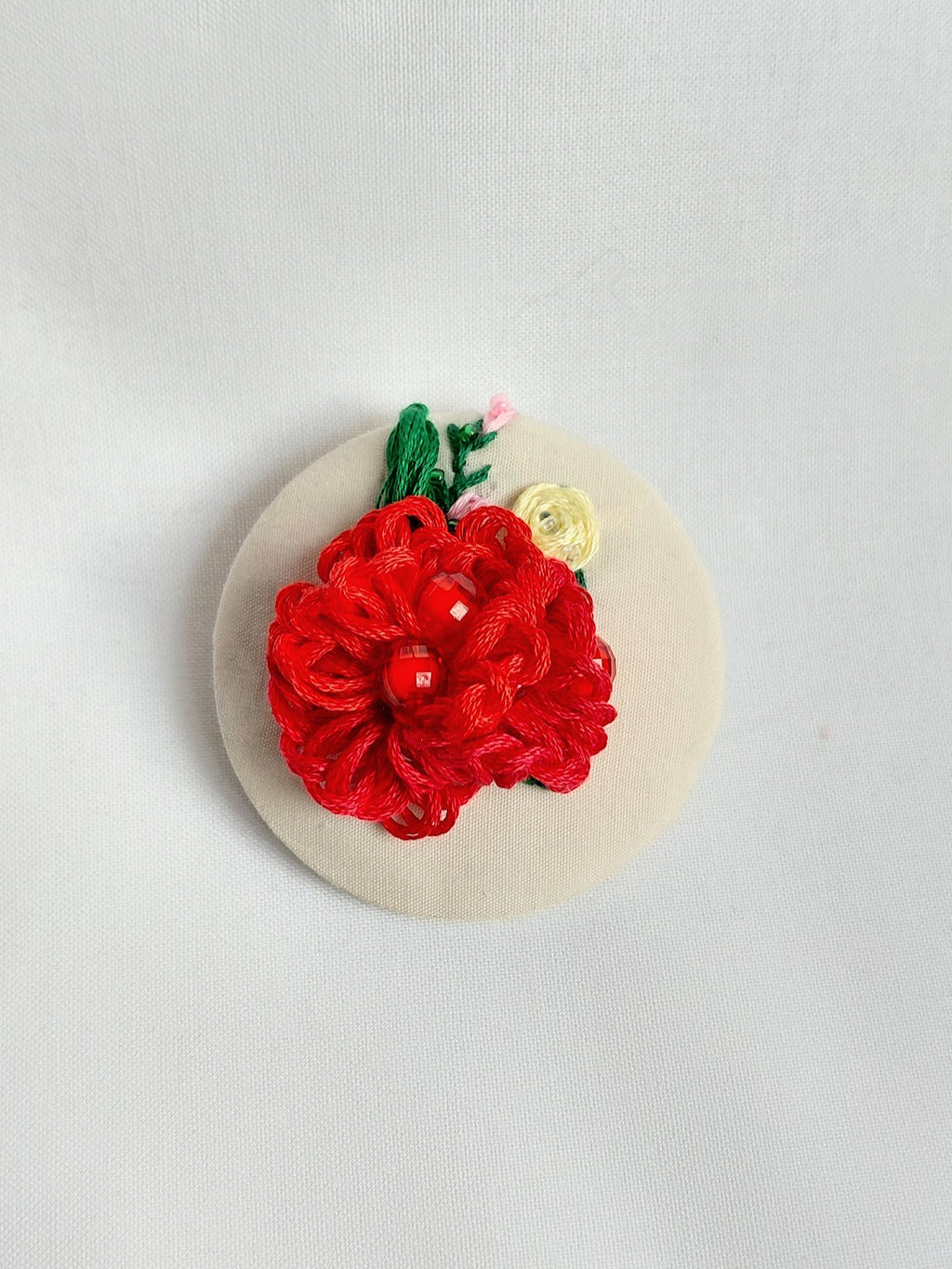 Decorative red flower brooch on cream background